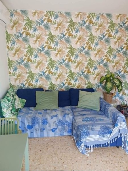 Recreational apartment with patterned wallpaper, a comfortable sofa, and cushions on a wooden decor floor.