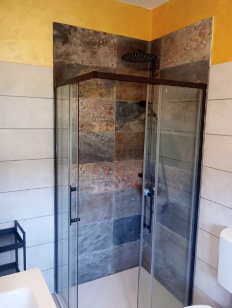 A shower enclosure with stoneware tiles in a holiday apartment.