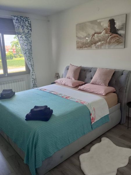 A recreational apartment with a comfortable bed, pastel-colored bedding, and a wooden decor floor.