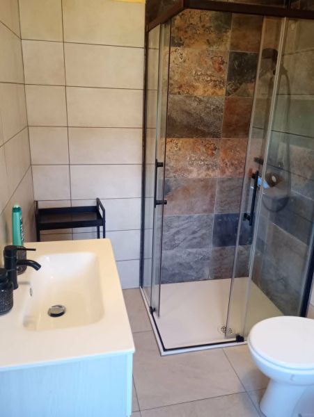 A bathroom in a holiday apartment with a modern shower and sink.