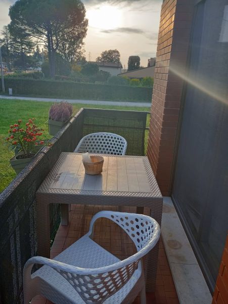 Balcony of a holiday apartment in Bibione with rattan seating and a view of greenery.