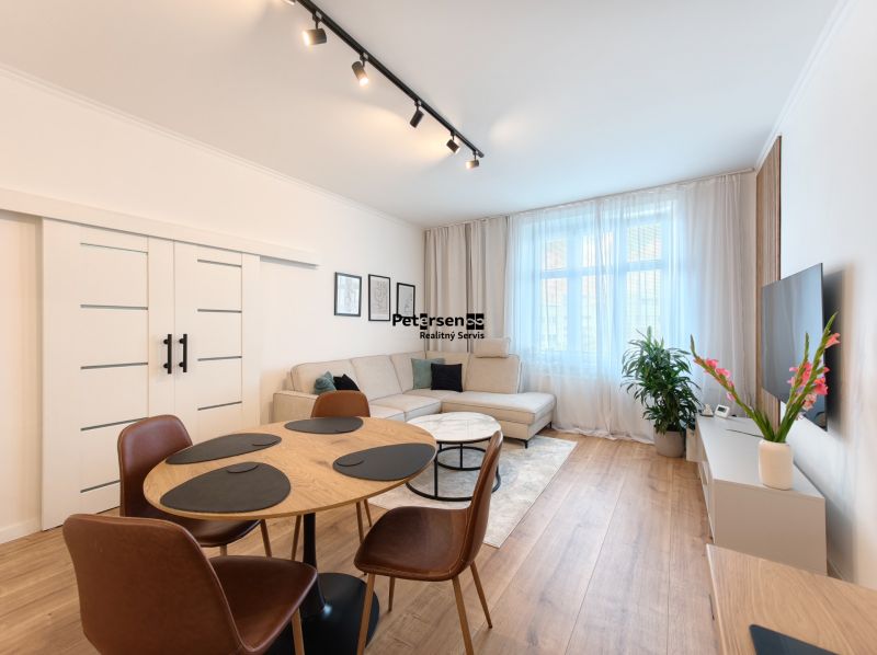Living room with a corner sofa, dining table, and wooden decor flooring in a 3-room apartment.