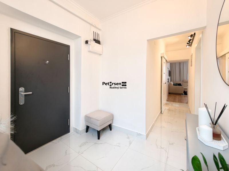A hallway with white walls, tiles, and dark doors in a 3-room apartment.