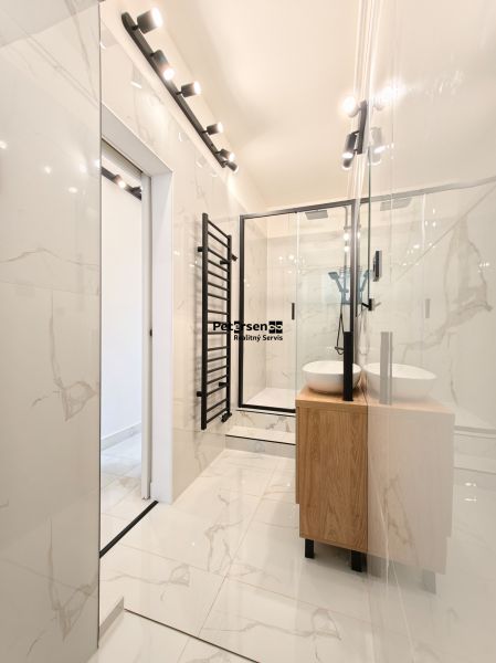 A bathroom with a bathtub, a sink, and glossy white walls in a 3-room apartment.