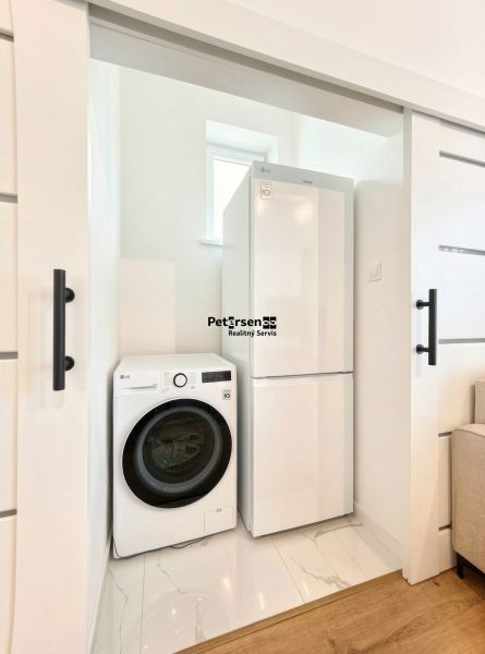 Laundry room in a 3-room apartment, washing machine and refrigerator, white sliding doors.