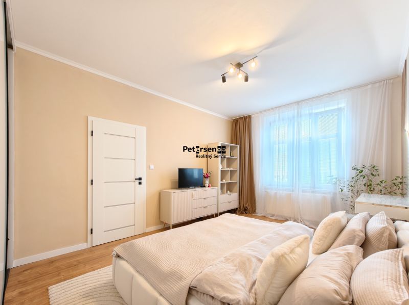 A bright room with a bed, TV, wardrobe, and wooden decor flooring in a 3-room apartment.