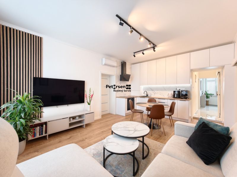 Living room with kitchen in a 3-room apartment, white cabinets, floor with wood decor.