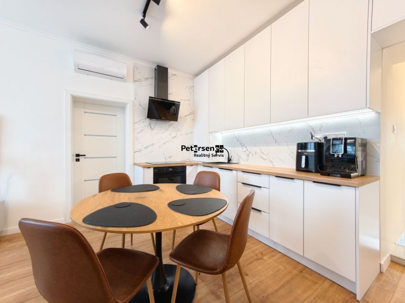 A kitchen in a 3-room apartment with white cabinets and a wood-patterned floor.