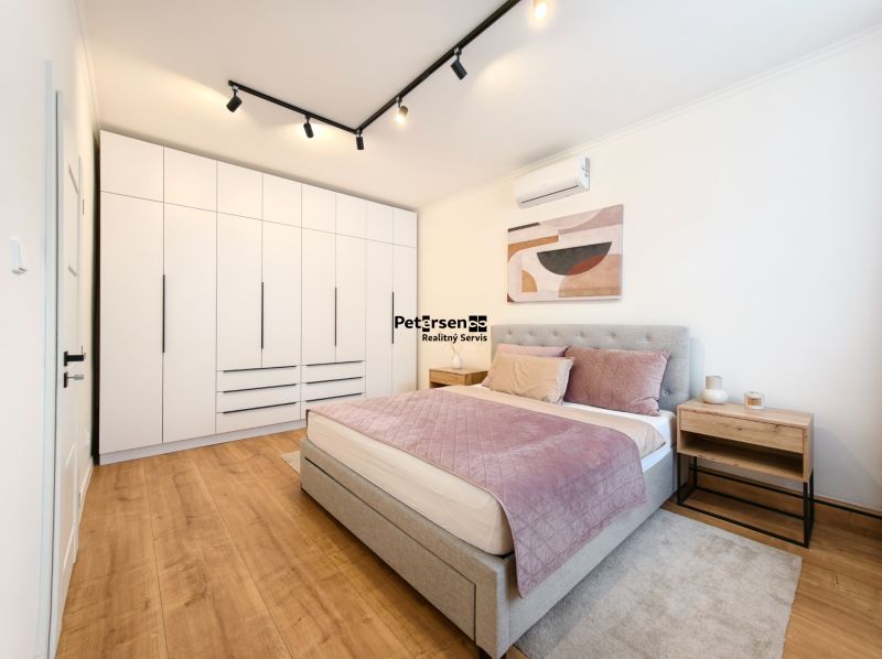 Bedroom with a built-in wardrobe, bed, and floor with a wood decor in a 3-room apartment.