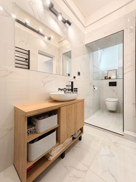 A bathroom with a modern sink and shower in a 3-room apartment, floor with wood decor.