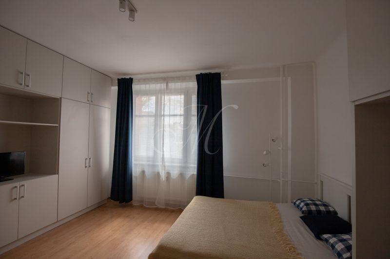 A room in a one-bedroom apartment with a bed, storage spaces, and a floor with a wooden decor.