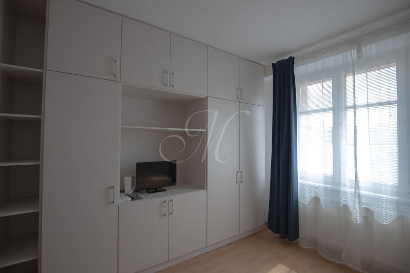 Built-in wardrobes with a television and a blue curtain in a studio apartment.