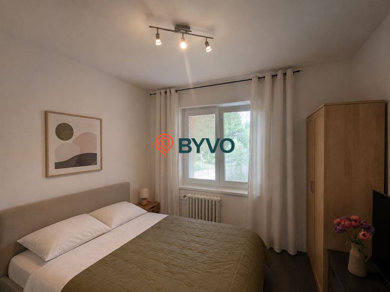 A bedroom in a 4-room apartment with a bed, a painting, and wooden furniture.