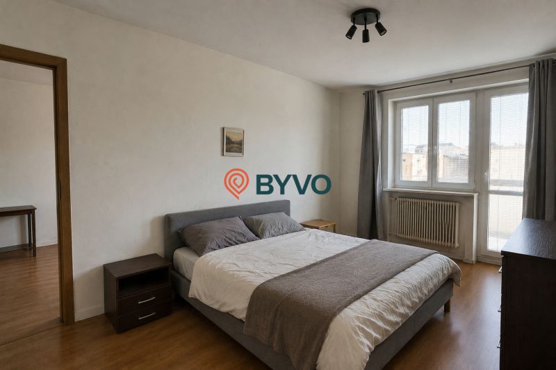 Bedroom in a 4-room apartment with a bed, wardrobe, and wooden decor flooring.