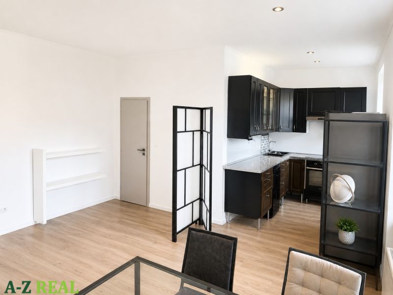 Open kitchen with black cabinets, wood-patterned flooring, and a table in a three-room apartment.