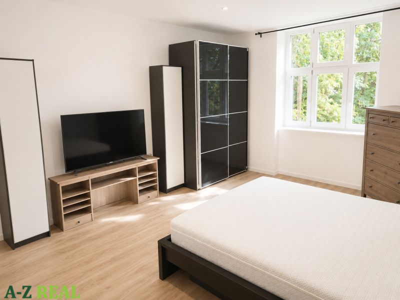 Bedroom in a 3-room apartment with light furniture and a television, floor with wooden decor.