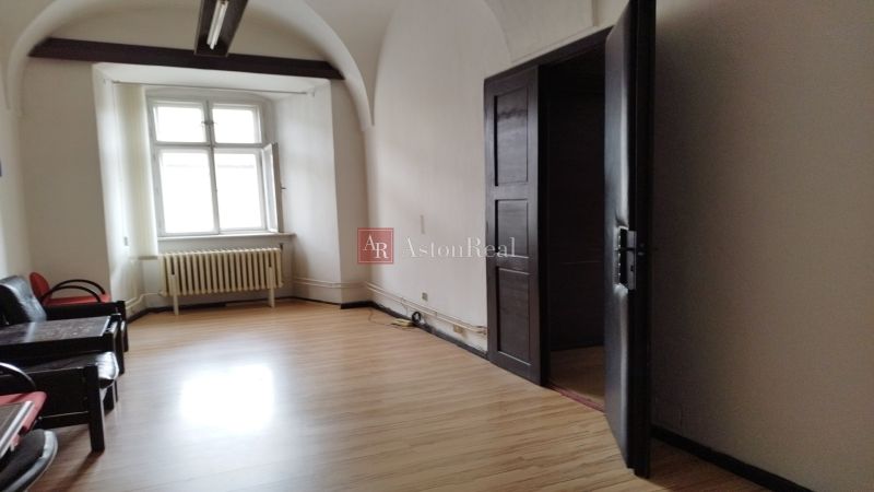 Interior of commercial premises with wood-effect flooring, older radiators, arched ceiling.
