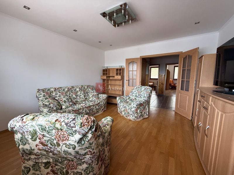 Living room in a 4-room apartment with floral furniture and a wooden decor floor.
