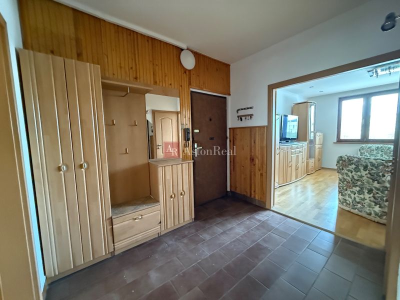Entrance hall in a 4-room apartment with wooden cabinets and a floor with a wooden decor.