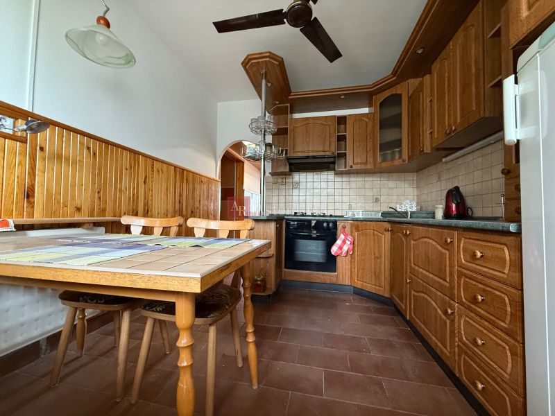 A kitchen in a 4-room apartment with wooden cabinets and a dining table with a ceramic top.