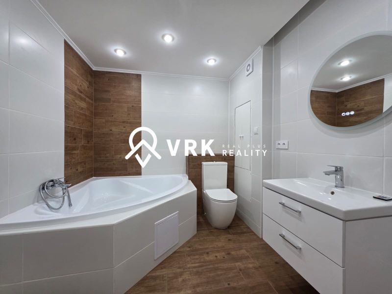Bathroom in a 3-room apartment with a bathtub, sink, and floor with a wooden decor.