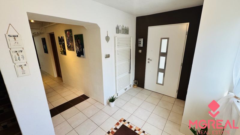 A hallway in a family house with tiles, decorations, and paintings on the walls.