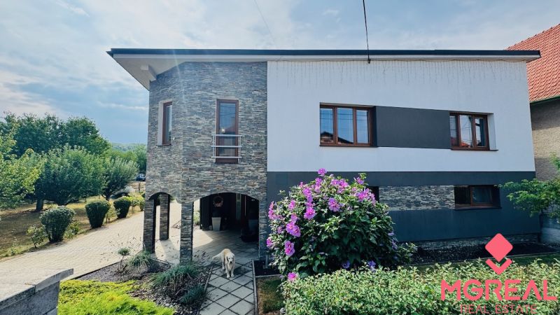A family house in Radobica with a stone facade, a garden, and flowers in front of the building.