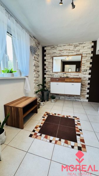 Interior of a family house with tiles, decorative stones on the wall, and wooden furniture.