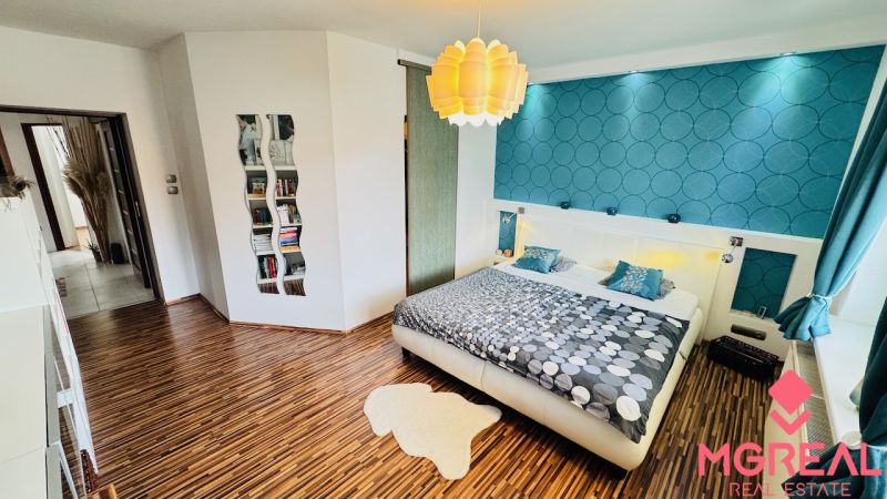 A bedroom in a family house with colorful wallpaper and a wooden decor floor.