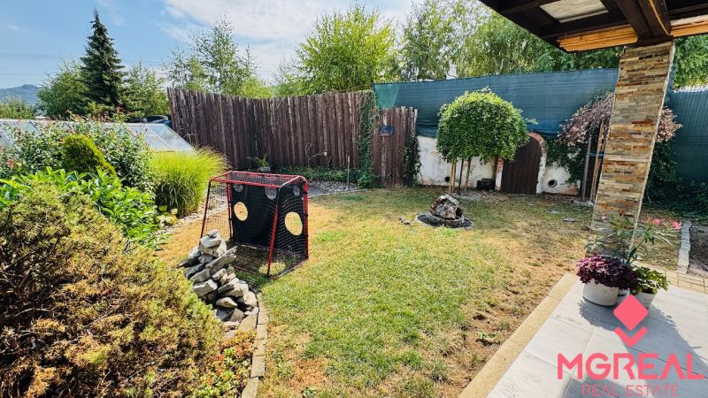 Garden of a family house in Radobica with a lawn, shrubs, and a wooden fence.