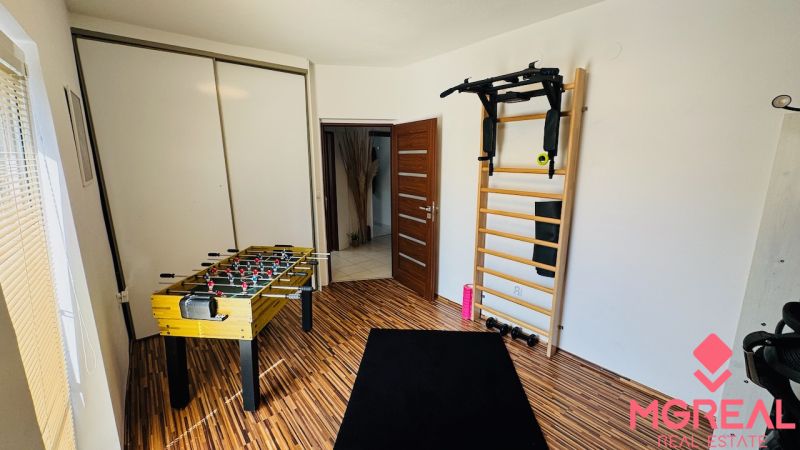 Home gym with a wall bar, foosball table, and floor with wood decor.