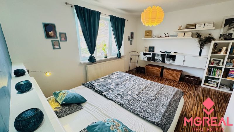 A bedroom in a family house with a wooden decor floor and colorful textile accessory.