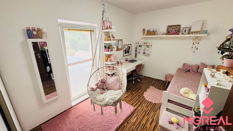 Children's room with a swing, bed, and desk, floor with wooden decor.