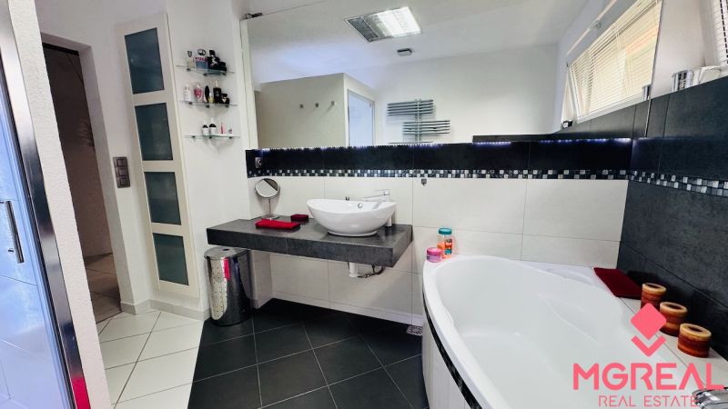 A bathroom in a family house with a modern sink, bathtub, and decorative accessories.