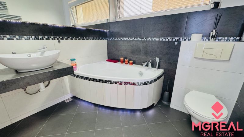 Bathroom in a family house with a wall-hung toilet, bathtub, and sink.