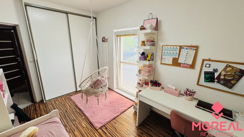 Children's room with a rocking chair, pink carpet, and wooden decor flooring.