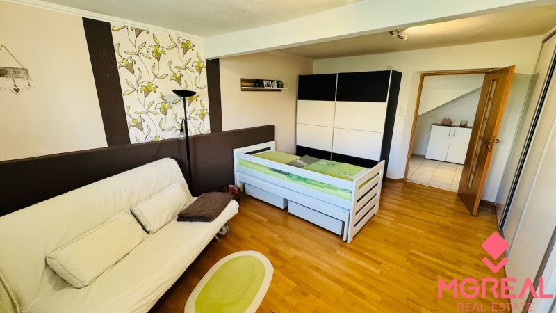 A room with a sofa and a bed, wooden decor flooring, family house.