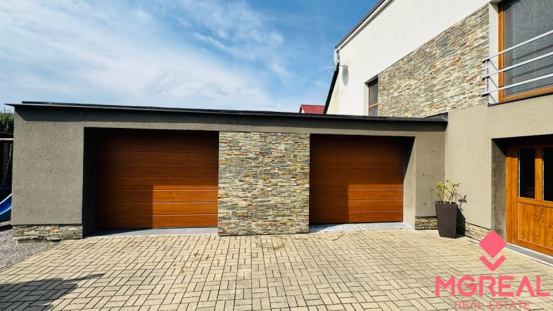 The family house in Radobica has a garage with wooden doors and a brick decor.
