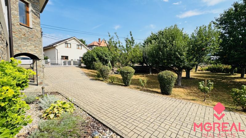 Family house in Radobica with a garden, a paved road, and stone cladding on the facade.