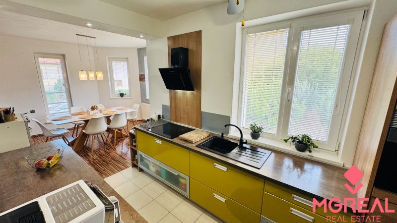 Interior of a family house with a kitchen, dining table, and wooden decor flooring.