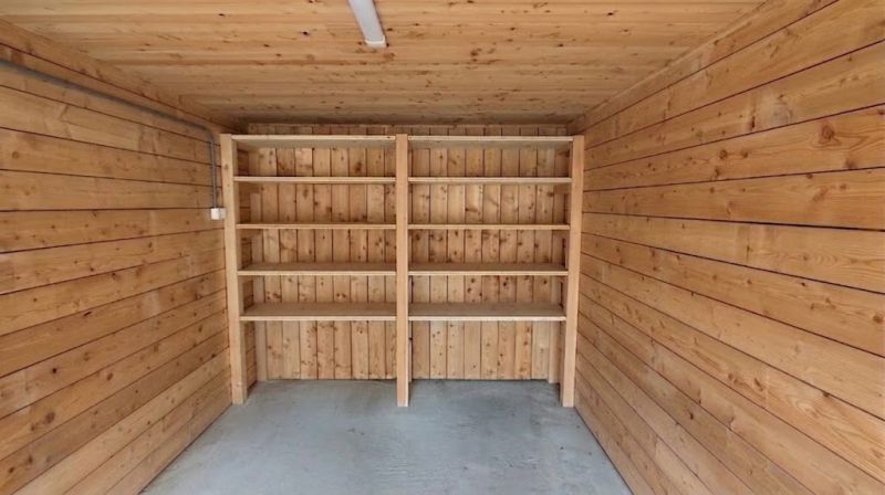 Garages with wooden decor, empty shelves, concrete floor.