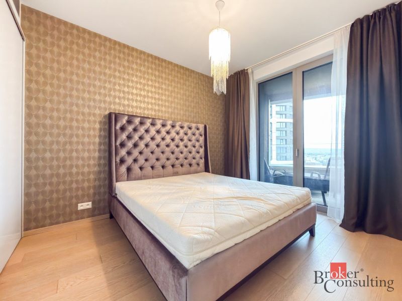 Bedroom in a 2-room apartment with a bed, chandelier, wooden decor flooring.
