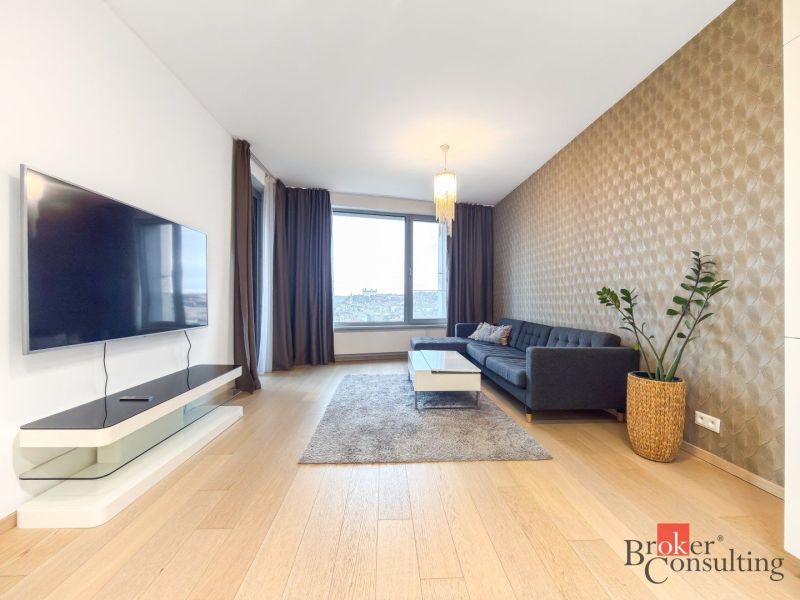 A stylish living room with a wood-patterned floor, a dark gray sofa, and a wall-mounted television.