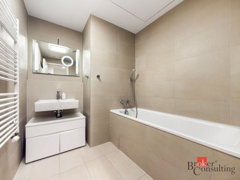 Bathroom with a bathtub and a sink, light tiles, ideal for a 2-room apartment.