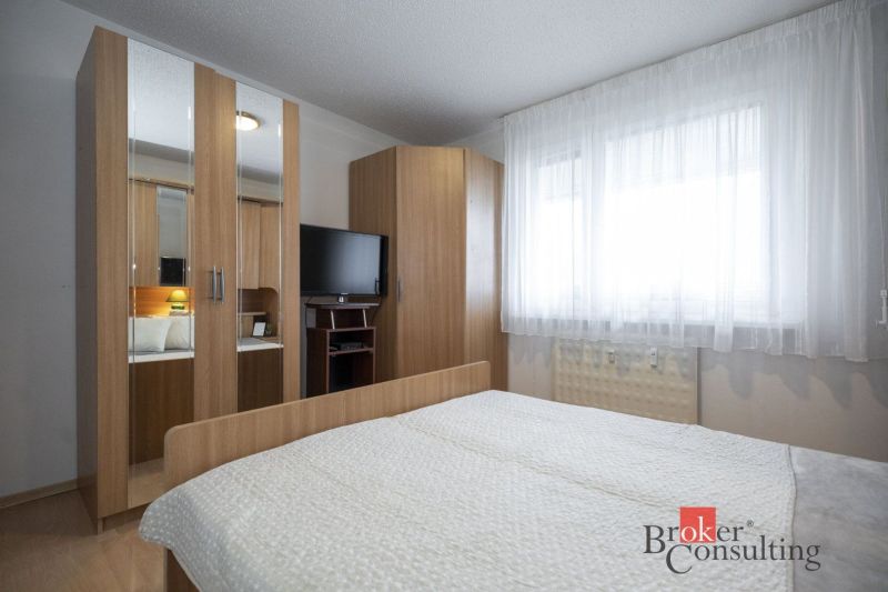 Bedroom in a 4-room apartment with a television and a wardrobe in a wooden decor.