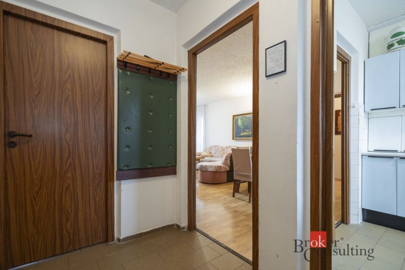 A hallway leading to the living room with a wooden decor floor in a 4-room apartment.