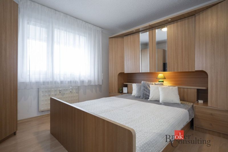 Bedroom with a bed, built-in wardrobe, and floor with wood decor in a 4-room apartment.