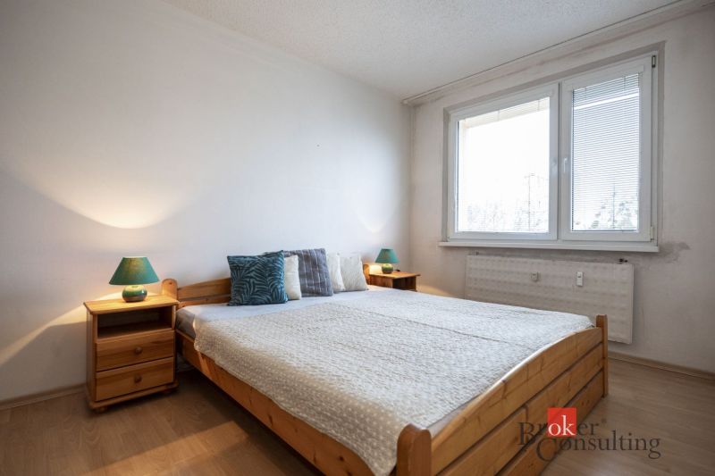 A bedroom with a bed, nightstands, and a wooden decor floor in a 4-room apartment.