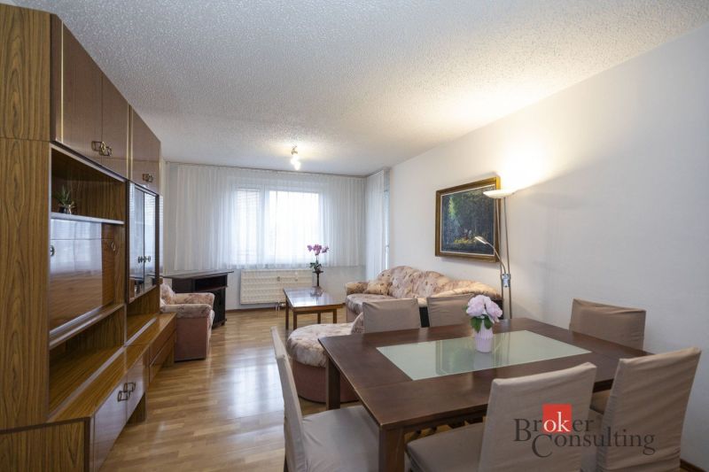Living room in a 4-room apartment with a wooden decor floor and dining for four people.