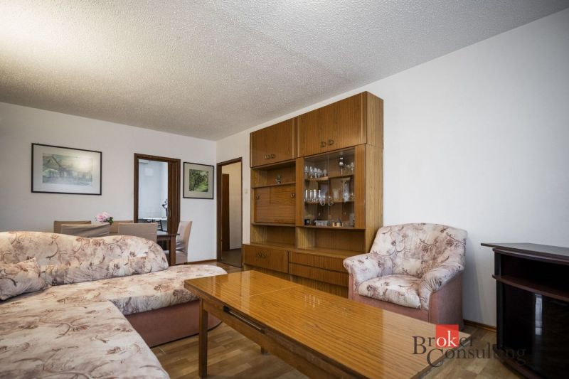 Living room with a sofa, armchair, furniture, and floor with wood decor in a 4-room apartment.